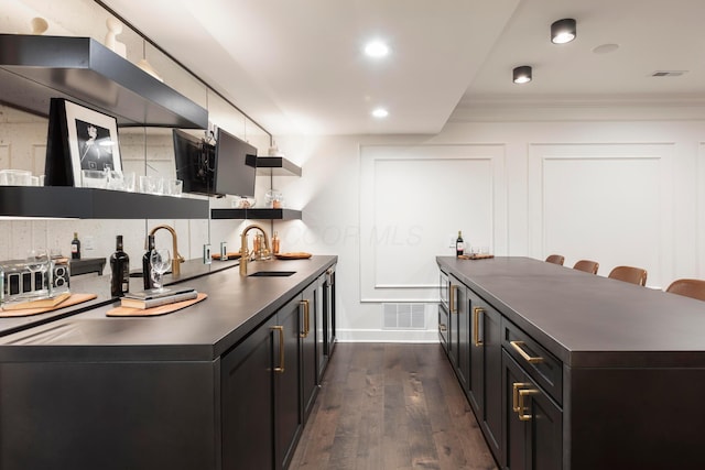 kitchen featuring ornamental molding, sink, dark wood-type flooring, and wall chimney exhaust hood