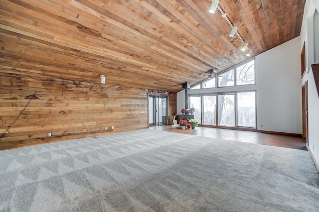 unfurnished living room featuring carpet flooring, rail lighting, high vaulted ceiling, wood walls, and wood ceiling