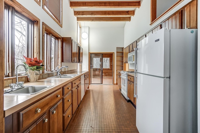 kitchen with light tile patterned flooring, beam ceiling, white appliances, and sink