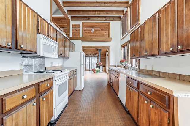 kitchen featuring beam ceiling, white appliances, a wood stove, and sink