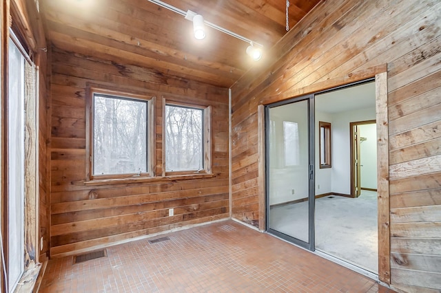 carpeted spare room featuring wood walls