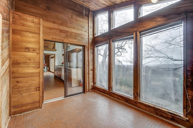 doorway to outside with wood ceiling and wood walls