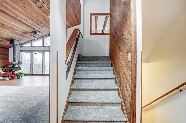 staircase featuring carpet, a wood stove, high vaulted ceiling, and wooden ceiling