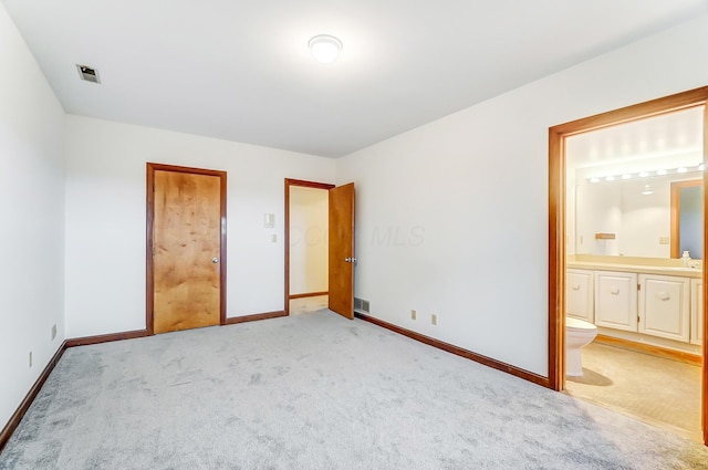 unfurnished bedroom with ensuite bathroom, sink, and light carpet