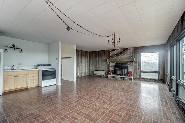 unfurnished living room featuring wood walls, sink, a wall mounted AC, and a brick fireplace