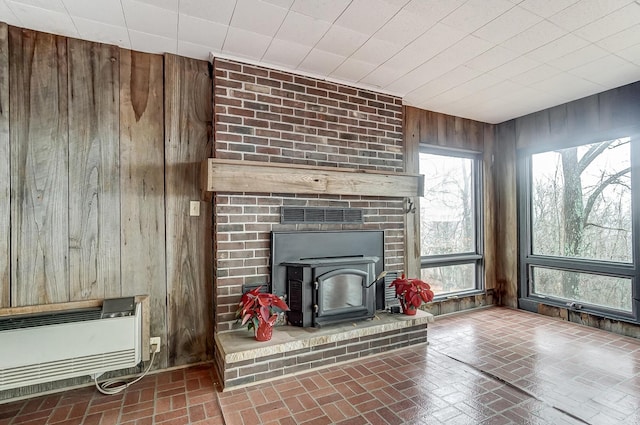 unfurnished living room with a wood stove and wooden walls