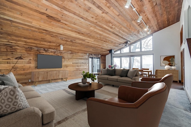 carpeted living room featuring rail lighting, ceiling fan, wooden walls, high vaulted ceiling, and wooden ceiling