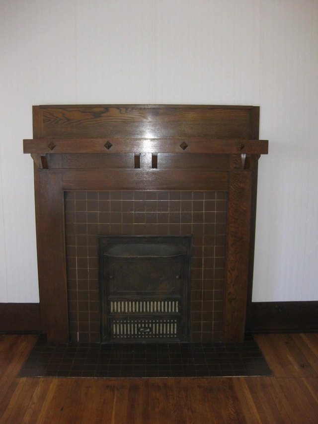 details with wood-type flooring and a tiled fireplace