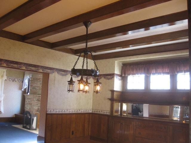 unfurnished dining area featuring beam ceiling and wooden walls