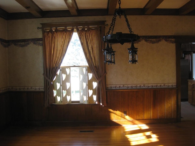 spare room with wooden walls, beamed ceiling, and hardwood / wood-style flooring