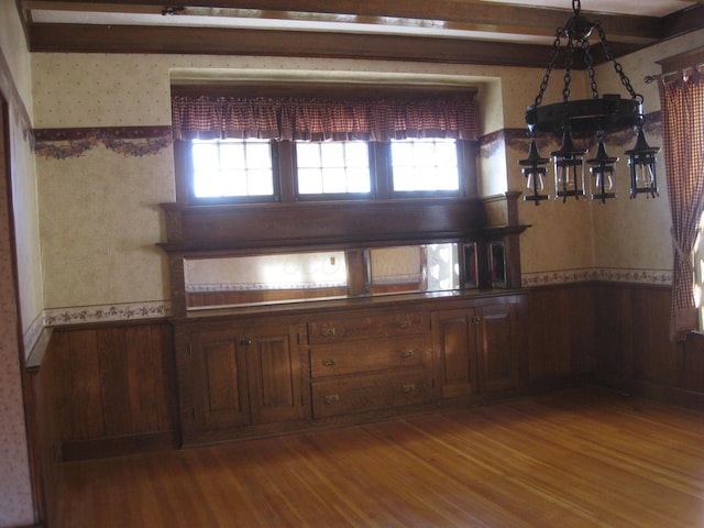 unfurnished dining area featuring beamed ceiling, hardwood / wood-style floors, and wooden walls