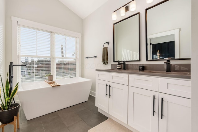 bathroom with tile patterned floors, a washtub, vanity, and lofted ceiling