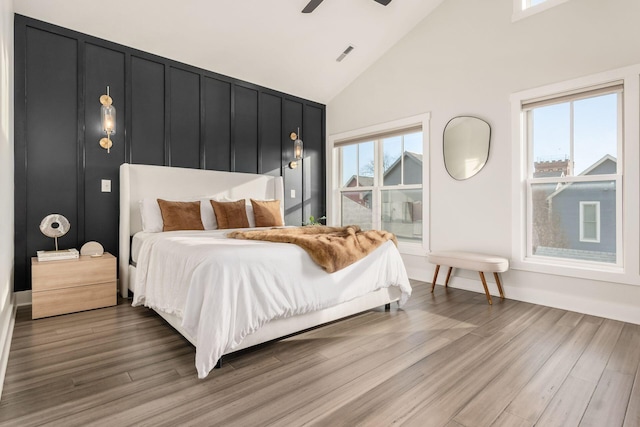 bedroom with ceiling fan, wood-type flooring, high vaulted ceiling, and multiple windows