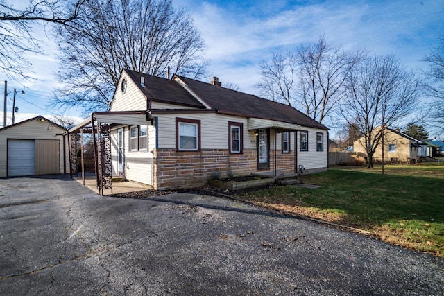 bungalow-style house featuring a garage, a front yard, and an outbuilding