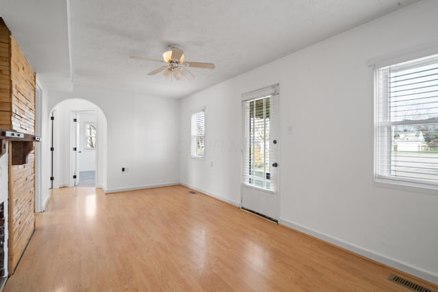 unfurnished living room with plenty of natural light, a textured ceiling, and light wood-type flooring