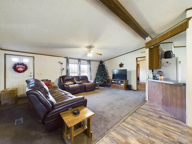 living room with beamed ceiling, ceiling fan, light hardwood / wood-style floors, and a textured ceiling