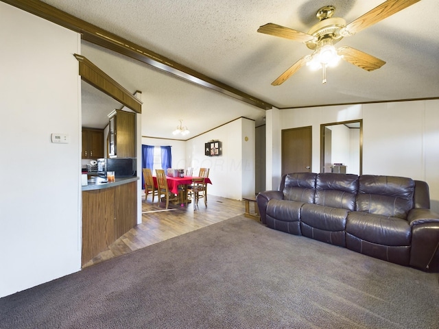 living room with vaulted ceiling with beams, ceiling fan, ornamental molding, a textured ceiling, and light hardwood / wood-style floors