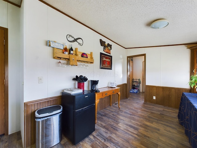 home office with a textured ceiling, crown molding, dark wood-type flooring, and wooden walls