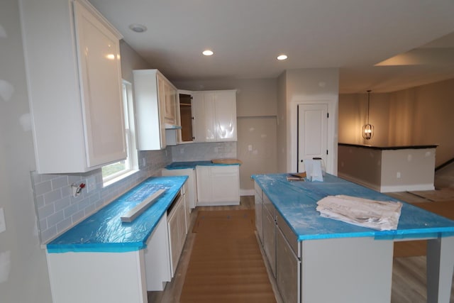 kitchen featuring a kitchen island, white cabinets, light wood-type flooring, and decorative backsplash