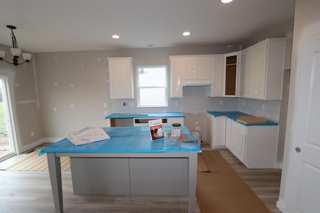 kitchen with white cabinetry, a kitchen island, light hardwood / wood-style flooring, and backsplash