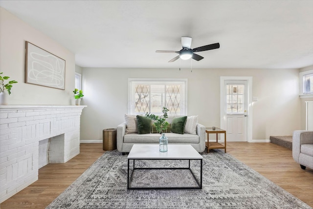 living room featuring a brick fireplace, plenty of natural light, ceiling fan, and light hardwood / wood-style flooring