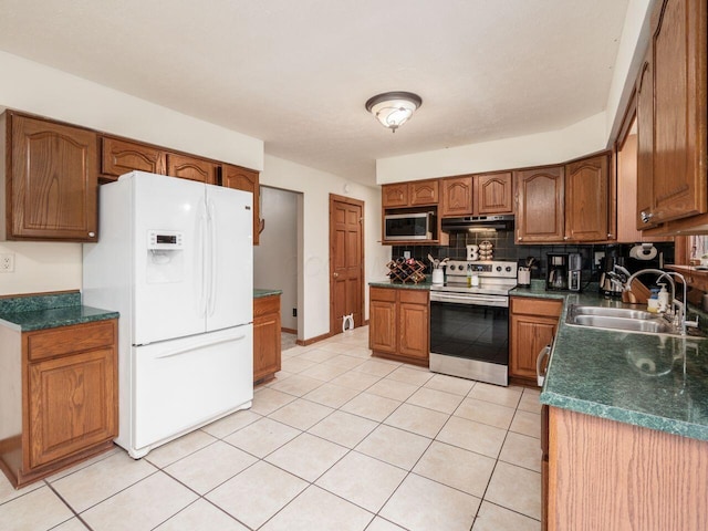 kitchen featuring tasteful backsplash, sink, light tile patterned floors, and appliances with stainless steel finishes