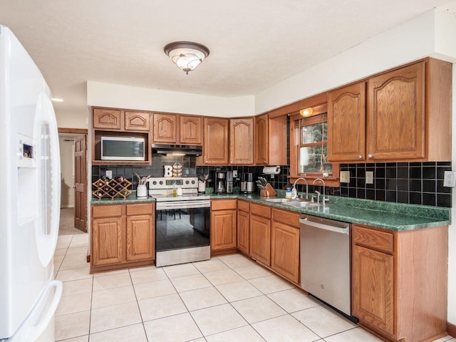 kitchen featuring tasteful backsplash, sink, light tile patterned floors, and stainless steel appliances