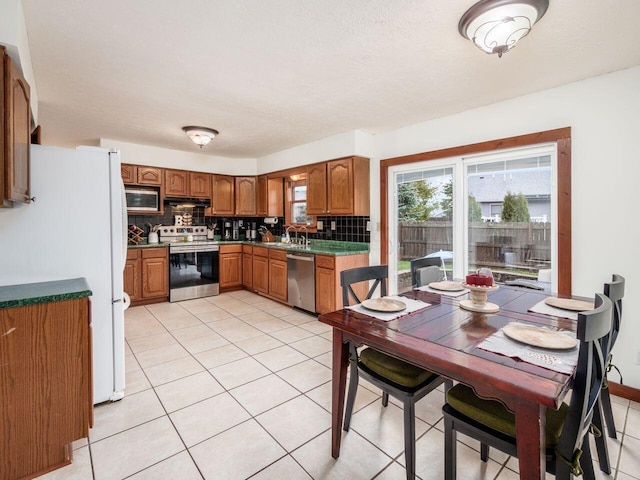 kitchen with tasteful backsplash, light tile patterned floors, extractor fan, and appliances with stainless steel finishes