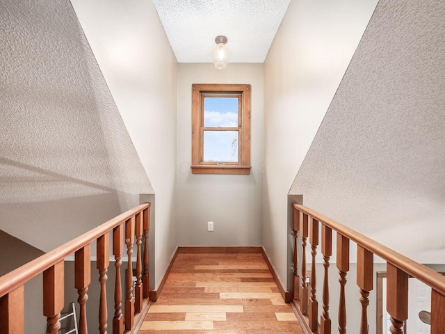 corridor featuring a textured ceiling and light hardwood / wood-style floors