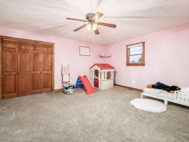 game room featuring ceiling fan, carpet floors, and a textured ceiling