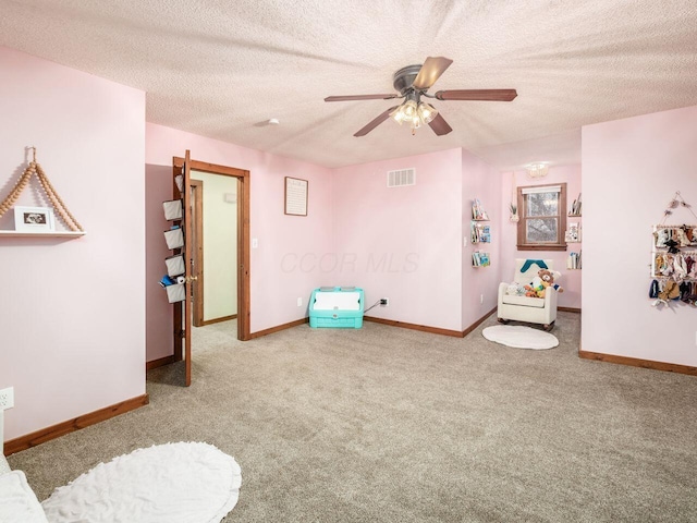 game room featuring a textured ceiling, light colored carpet, and ceiling fan