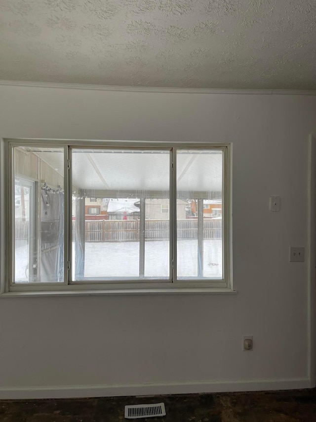 unfurnished room with crown molding, plenty of natural light, and a textured ceiling