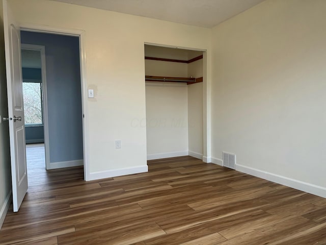 unfurnished bedroom featuring dark hardwood / wood-style floors and a closet