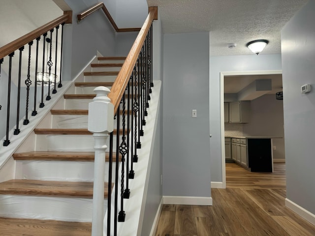 staircase with a textured ceiling and hardwood / wood-style flooring