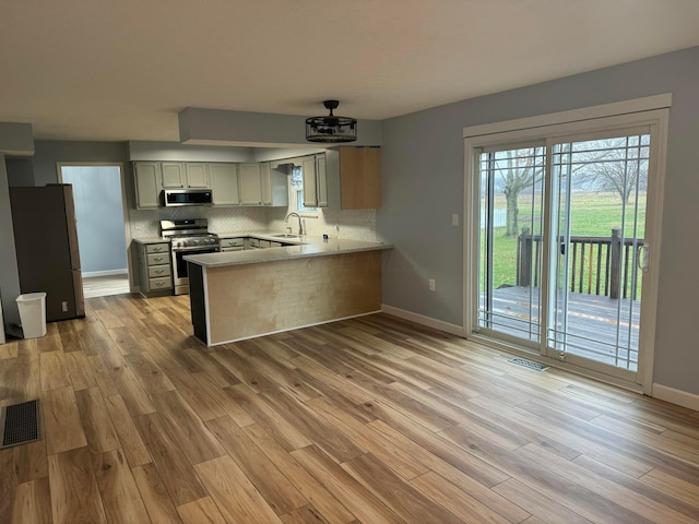 kitchen featuring decorative backsplash, sink, light wood-type flooring, and appliances with stainless steel finishes