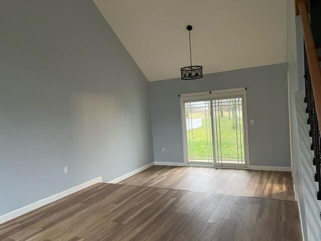 spare room featuring hardwood / wood-style flooring, high vaulted ceiling, and an inviting chandelier