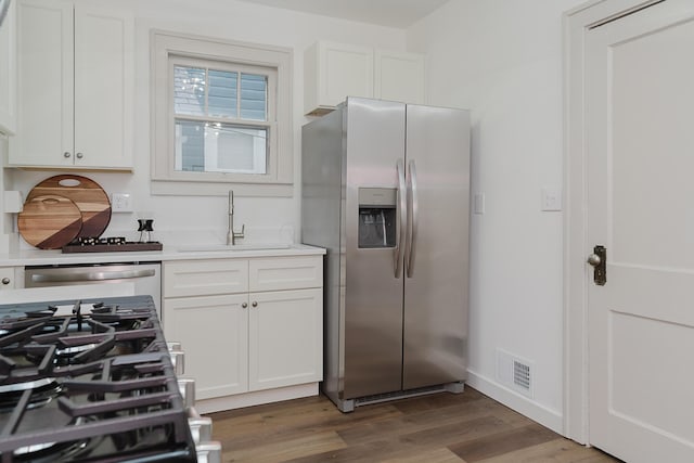 kitchen featuring stainless steel appliances, white cabinetry, dark hardwood / wood-style floors, and sink