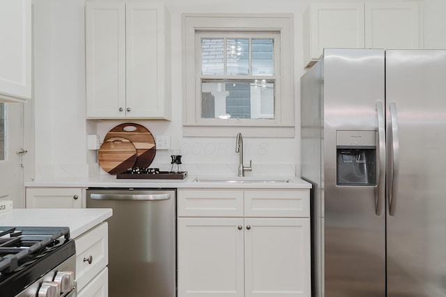 kitchen with light stone counters, sink, white cabinets, and stainless steel appliances