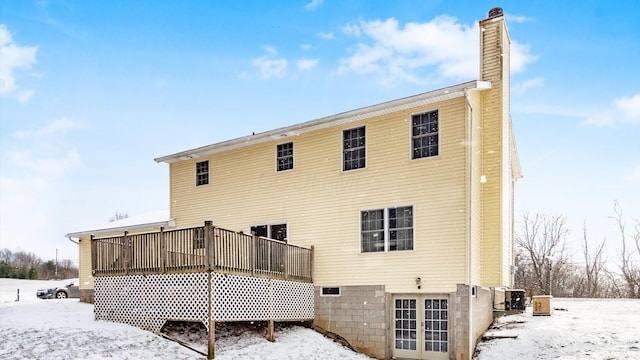 snow covered rear of property with a deck and cooling unit