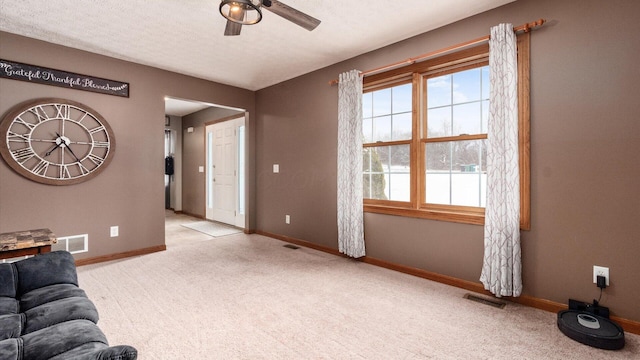 living room featuring light carpet, a textured ceiling, and ceiling fan