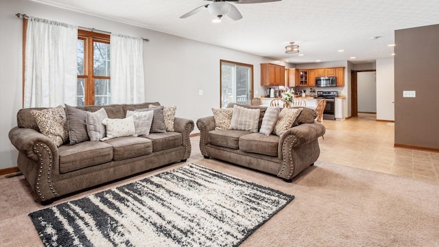 living room featuring ceiling fan, a textured ceiling, and light carpet