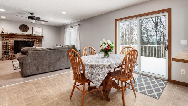 dining space featuring ceiling fan, a textured ceiling, and a brick fireplace