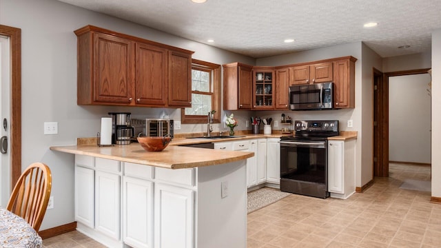 kitchen featuring a textured ceiling, kitchen peninsula, sink, and black electric range