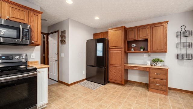 kitchen with black appliances, built in desk, and a textured ceiling