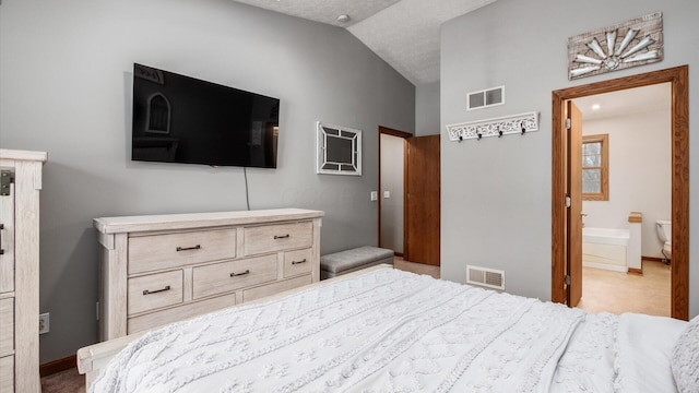 bedroom featuring ensuite bathroom and vaulted ceiling