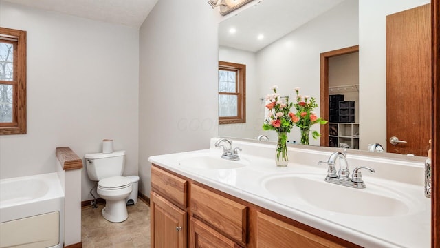 bathroom featuring a washtub, vanity, a healthy amount of sunlight, and toilet