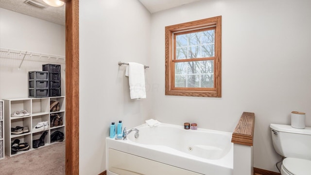 bathroom featuring a textured ceiling, toilet, and a bath