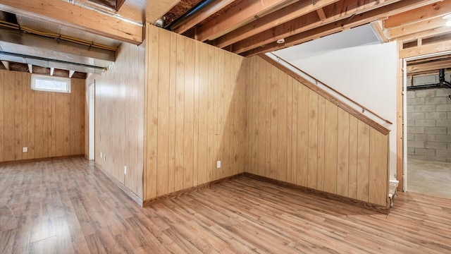 basement featuring light hardwood / wood-style floors and wooden walls