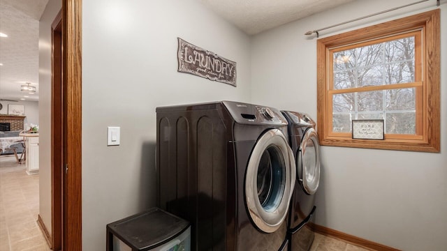 clothes washing area featuring a textured ceiling, washing machine and dryer, and a brick fireplace