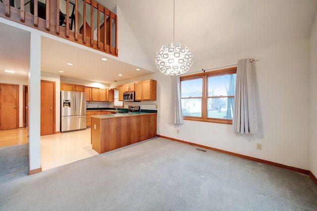 kitchen with kitchen peninsula, appliances with stainless steel finishes, pendant lighting, high vaulted ceiling, and a notable chandelier